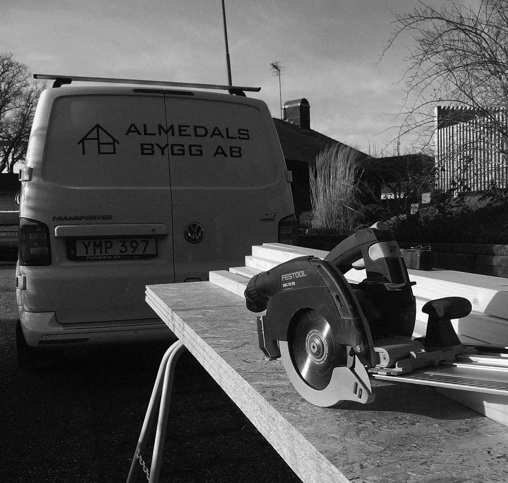 Flygfoto i svartvitt över flervåningshus med trädgård i villaområde.